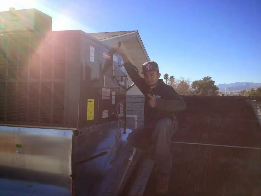 HVAC technician performing Air Duct Cleaning on a rooftop unit in Laguna Beach