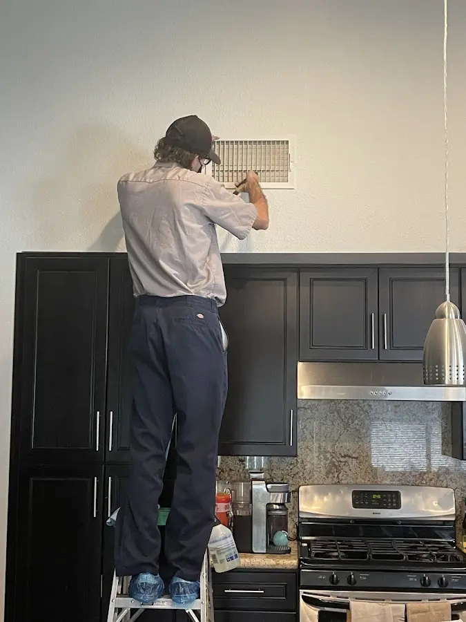 Technician inspecting an air vent during HVAC service in Laguna Beach